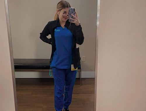 Young woman taking a mirror picture in dark blue scrubs